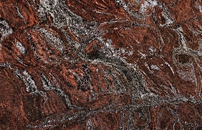 Boss Paradiso granite: swirling oxblood and rust figure threaded with silver-grey mist, polished to a deep gloss
