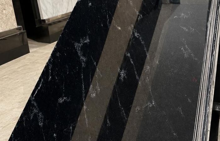 Fish Black granite: a stack of polished black slabs crossed by fine silver-white threads, photographed in the showroom