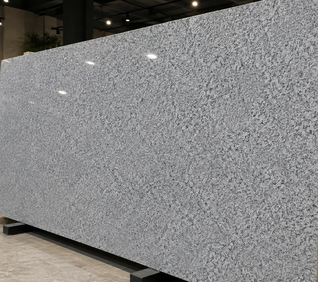 Spanish White granite: a bright grey-white polished slab with a fine, even speckle, standing in the showroom