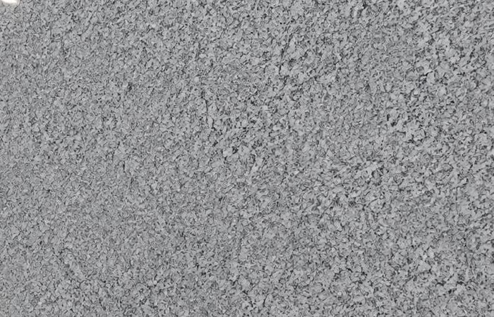 Spanish White granite: a bright grey-white polished slab with a fine, even speckle, standing in the showroom